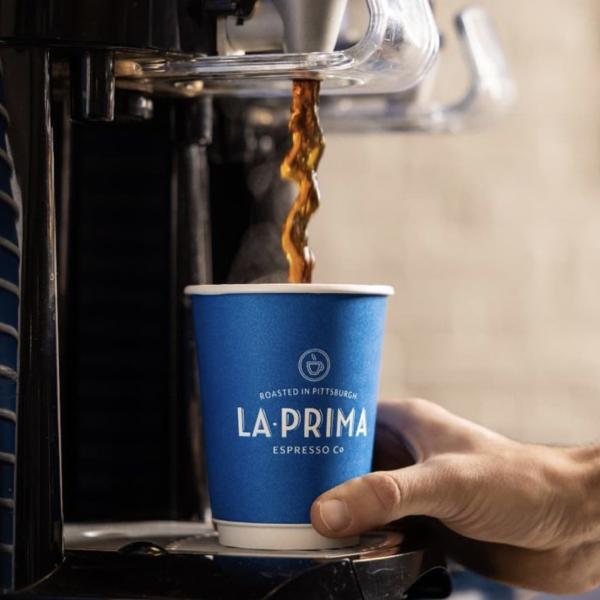 Blue La Prima branded cup with coffee being poured in.