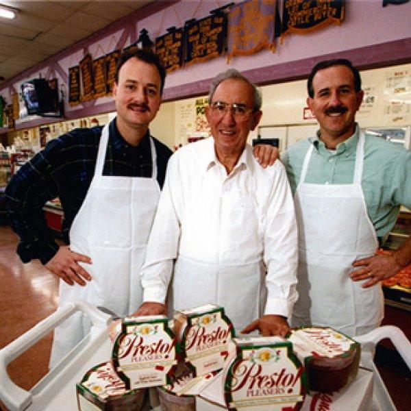 Three men standing side by side in front of their products